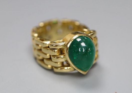 A yellow metal and solitaire pear shaped cabochon emerald set ring, with articulated shank, size G/H, gross 9 grams,